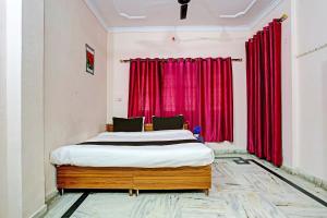 a bedroom with a bed with red curtains at OYO Hotel Trishakti Homestay in Lucknow