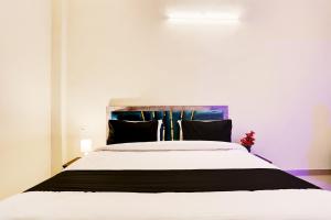 a bedroom with a large white bed with black pillows at Flagship Hotel RAAS INN in Kānpur