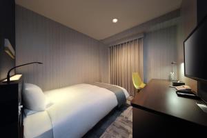 福島市にあるJR東日本ホテルメッツ福島の白いベッドとデスクが備わるホテルルームです。