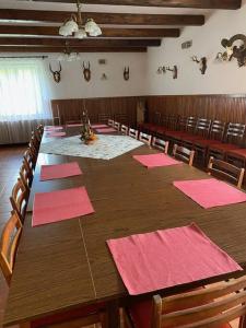 una gran mesa de madera con servilletas rosas. en Erdei vadászház medencével, jakuzzival (partyház), en Pusztavám