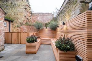 a patio with a wooden fence and plants at Great Escapes Oundle Flat 3 in Oundle