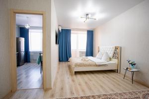 a bedroom with a bed in a room with blue curtains at 1-ком Тобол Арена, Костанай Плаза, Allur auto, НИШ БЕРЕКЕ in Kostanay