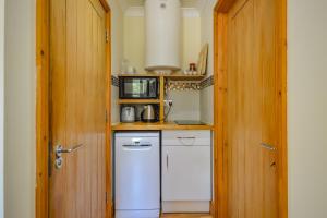 a small kitchen with white appliances and a door at Cosy Cabin Perfect To Explore in Garnant