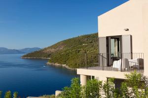 a house with a balcony overlooking a body of water at Villa Kastos - Stylish Luxury Villa with Direct Sea Access in Sivota