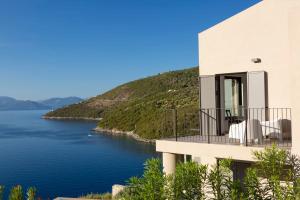 シヴォタにあるVilla Kastos - Stylish Luxury Villa with Direct Sea Accessの水を見渡すバルコニー付きの家