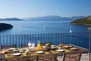 a dining table with a view of the water at Villa Kastos - Stylish Luxury Villa with Direct Sea Access in Sivota