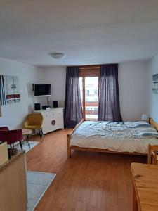 a bedroom with a bed and a desk and a television at Torgon Grand studio Confortable in Torgon