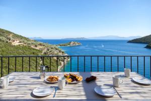 uma mesa com um prato de comida com vista para o oceano em VILLAS MIRO - Luxury Villas with Direct Sea Access for 14 people em Sivota