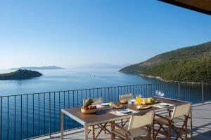 Una mesa en un balcón con vista al mar. en Villa Kalamos - Modern Villa in Sivota Bay with Direct Access to Sea, en Sivota