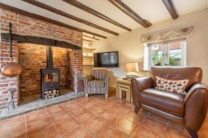 a living room with a brick fireplace and a chair at Mayes Cottage in Brancaster