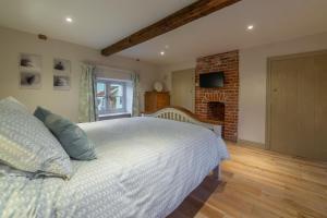 a bedroom with a white bed and a fireplace at Mayes Cottage in Brancaster
