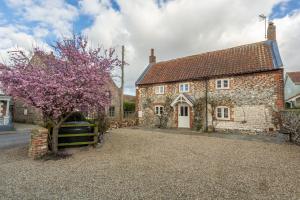 an old stone house with a tree in front of it at Mayes Cottage in Brancaster