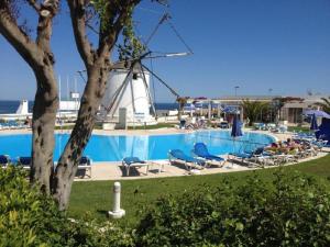 een windmolen naast een zwembad met stoelen en een windmolen bij The Albufeira Concierge - Moinho Pool & Gardens in Albufeira