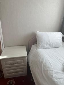 a bed with a white pillow and a night stand at Bella Vista in Llandudno