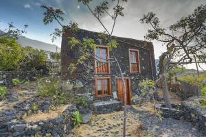 una pequeña casa de piedra en medio de un jardín en Casa Rural De Piedra, en La Frontera