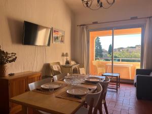 a dining room with a table with chairs and a window at L'Appartement des Sables in Le Lavandou