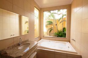 baño con bañera, lavabo y ventana en Motel Haraam, en Araraquara