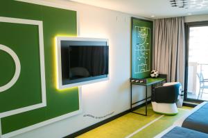 a room with a tv on a wall with a chair at Hotel Magic Sports 4 in Oropesa del Mar