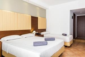 two beds in a hotel room with white sheets at White Olive Premium Laganas in Laganas