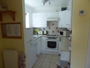 een keuken met witte kasten en een fornuis met oven bij Sea view bungalow in The Mumbles