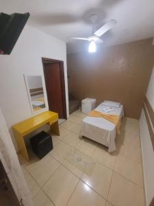 サンパウロにあるHospedaria Ipirangaの小さなお部屋で、ベッド2台、黄色いテーブルが備わります。