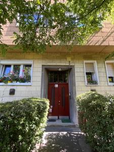 a house with a red door and two windows at City Green Little Flat in Budapest