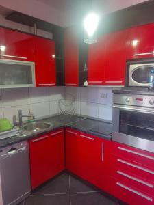 a red kitchen with a sink and a microwave at Hana's Luxury apartment in Skopje