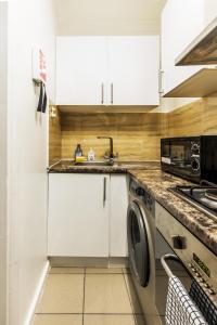 a kitchen with a sink and a washing machine at Old Street Apartments By Morethanstays in London