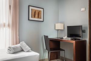 a hotel room with a desk with a television and a bed at Hotel Madanis Liceo in Hospitalet de Llobregat