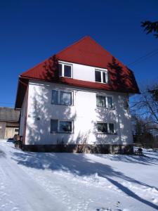 um edifício branco com um telhado vermelho na neve em Na Dziole em Lipnica Wielka