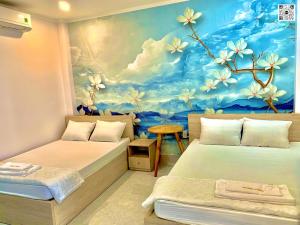 Habitación con 2 camas y una pintura de flores. en Hotel Phước Thịnh en Vĩnh Long