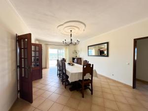 uma sala de jantar com uma mesa e cadeiras e um lustre em Villa Entrecolinas em São Bartolomeu de Messines