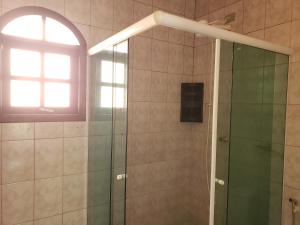 a shower with a glass door and a window at Pousada e Hostel Casa da Jura in Ilhabela