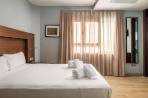 1 dormitorio con 1 cama grande y toallas. en Hotel Madanis Liceo, en Hospitalet de Llobregat