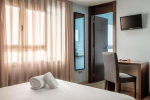 a hotel room with a bed and a chair and a desk at Hotel Madanis Liceo in Hospitalet de Llobregat