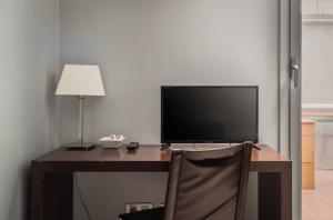 a desk with a television and a lamp and a chair at Hotel Madanis Liceo in Hospitalet de Llobregat