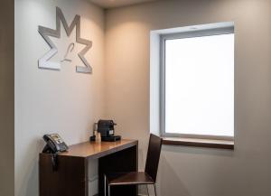 a office with a desk with a phone and a window at Hotel Madanis Liceo in Hospitalet de Llobregat