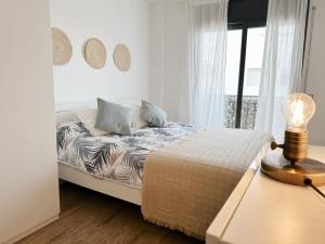 a white bedroom with a bed and a window at Ático con Vistas al Mar a un Paso del Centro in Blanes