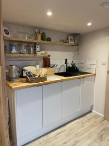 cocina con armarios blancos y encimera en El Nido - Self Catering cabin in Southbourne, 5 mins from beach en Iford