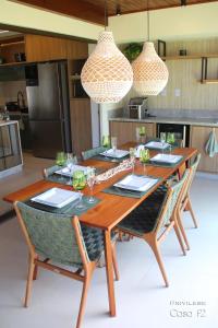 a wooden table with chairs and wine glasses at Exclusivo 2 suites a Beira Mar Imbassaí Privilege in Imbassai