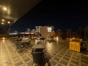 a rooftop patio with tables and chairs at night at Luxo Kochi in Ernakulam