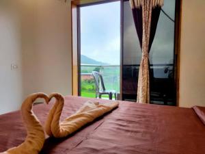 a bedroom with a bed with two towel animals on it at HOTEL NATURE SHIELD in Lonavala