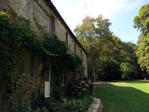 un bâtiment en pierre avec des fleurs sur son côté dans l'établissement Le Prieuré Saint Blaise, à Le Puy-Saint-Bonnet