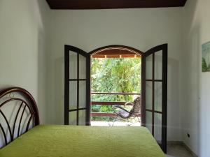 um quarto com uma cama verde e uma janela aberta em Pousada e Hostel Casa da Jura em Ilhabela