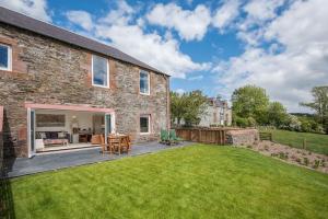 a brick house with a patio and a yard at Smiddy in Melrose