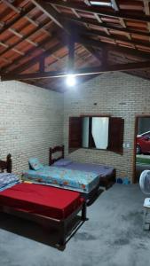 a room with two beds and a mirror in it at Chalé dos Coqueiros em Paracuru in Paracuru