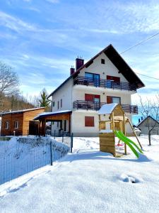 a house with a playground in the snow at Holiday home Maklen with big garden and jacuzzi in Brod Moravice