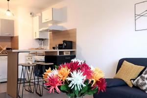 a living room with a blue couch with a vase of flowers at Pour 4 personnes entre Paris et Disneyland. in Pontault-Combault