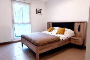 1 dormitorio con cama de madera y almohadas amarillas en Pour 4 personnes entre Paris et Disneyland., en Pontault-Combault
