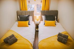 two beds in a room with yellow and white at Lovely Three Bed at Tanglewood in Hillingdon